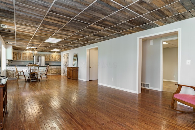 unfurnished living room featuring baseboards, visible vents, and dark wood-type flooring