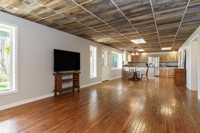 unfurnished living room featuring baseboards, visible vents, and dark wood-style flooring