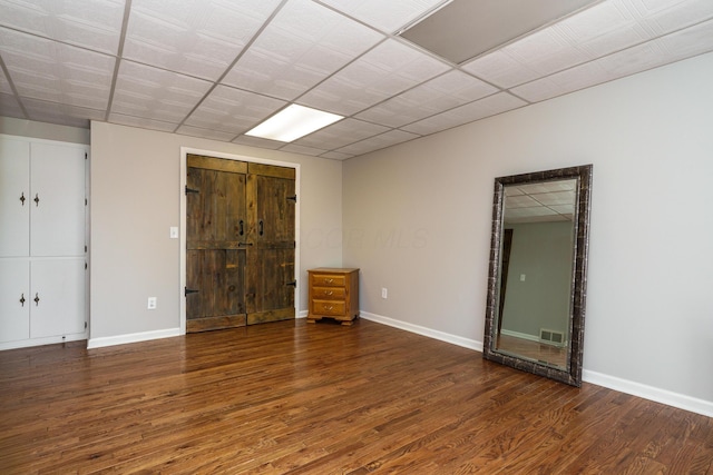 unfurnished room featuring wood finished floors, visible vents, and baseboards