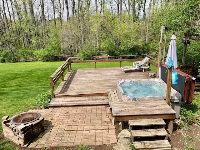 deck with hot tub deck surround, an outdoor fire pit, and a yard