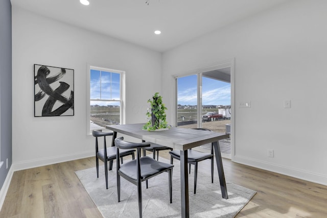 dining room featuring baseboards, light wood-style flooring, and a healthy amount of sunlight