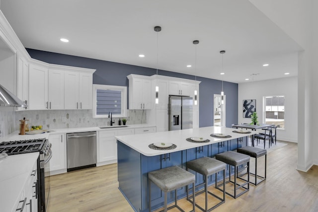 kitchen with white cabinets, a kitchen bar, a kitchen island, appliances with stainless steel finishes, and a sink