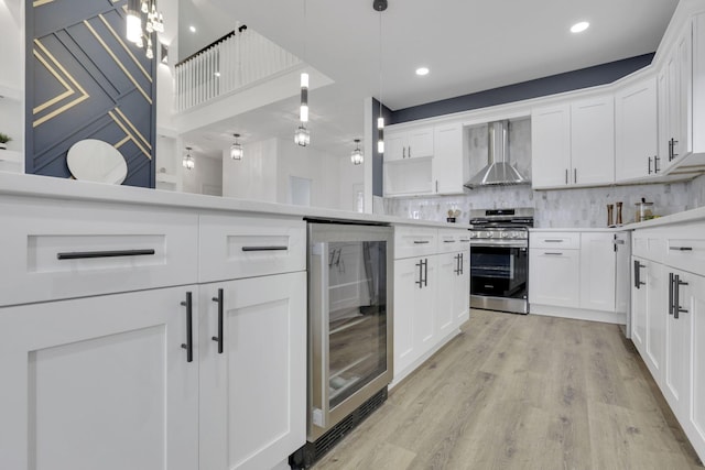 kitchen with wine cooler, stainless steel gas stove, light wood-type flooring, wall chimney range hood, and decorative backsplash