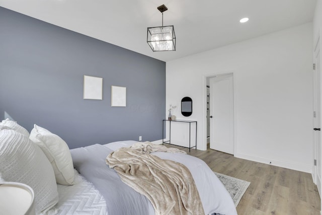bedroom featuring baseboards, wood finished floors, a chandelier, and recessed lighting