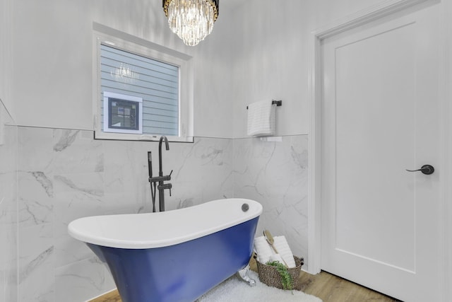 bathroom featuring an inviting chandelier and a soaking tub