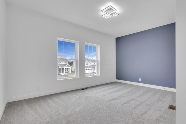 spare room with baseboards, carpet flooring, and visible vents