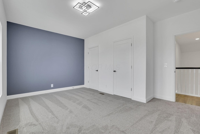 unfurnished bedroom with carpet, baseboards, and visible vents