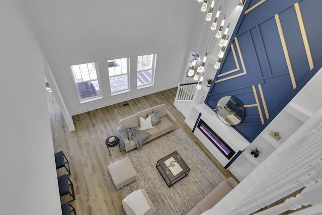 living room with baseboards, a high ceiling, wood finished floors, and stairway