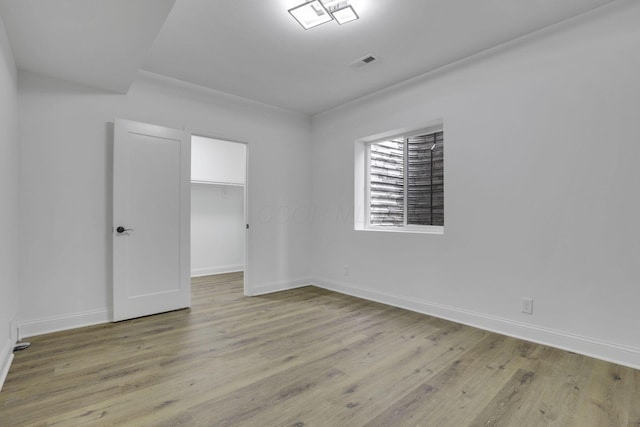 empty room featuring baseboards, visible vents, and wood finished floors