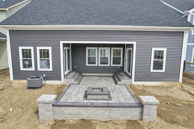 rear view of house featuring central AC, roof with shingles, and a patio area