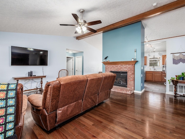 living room with a textured ceiling, vaulted ceiling with beams, ceiling fan, and wood finished floors