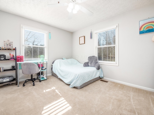 carpeted bedroom featuring a ceiling fan, baseboards, visible vents, and a textured ceiling