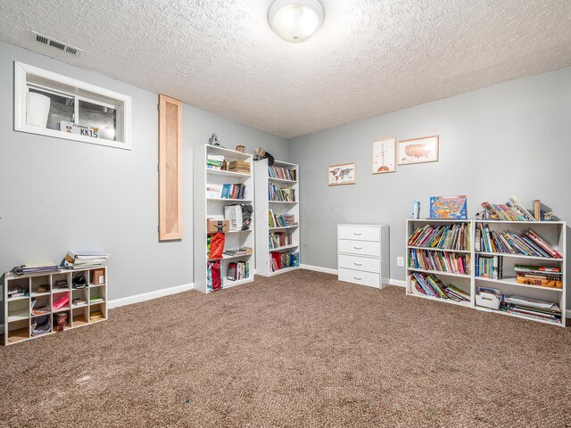recreation room featuring visible vents, a textured ceiling, baseboards, and carpet