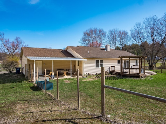 back of house with a patio, a lawn, a chimney, and a shingled roof