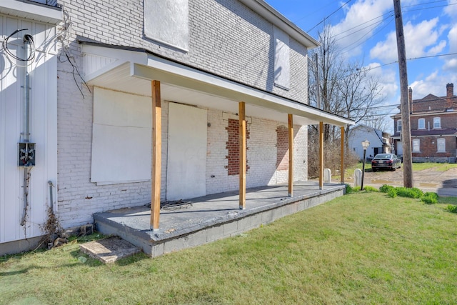 view of property exterior featuring a porch, a yard, and brick siding