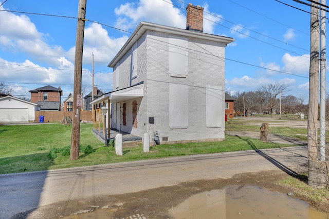 view of property exterior featuring brick siding, a chimney, and a lawn