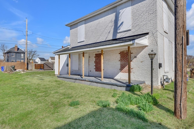 rear view of house with a yard, fence, brick siding, and a patio