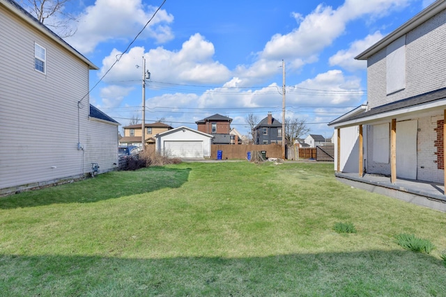 view of yard featuring a residential view, an outdoor structure, fence, and a detached garage