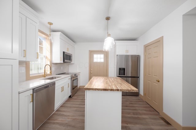 kitchen with a kitchen island, a sink, appliances with stainless steel finishes, light wood-type flooring, and butcher block counters