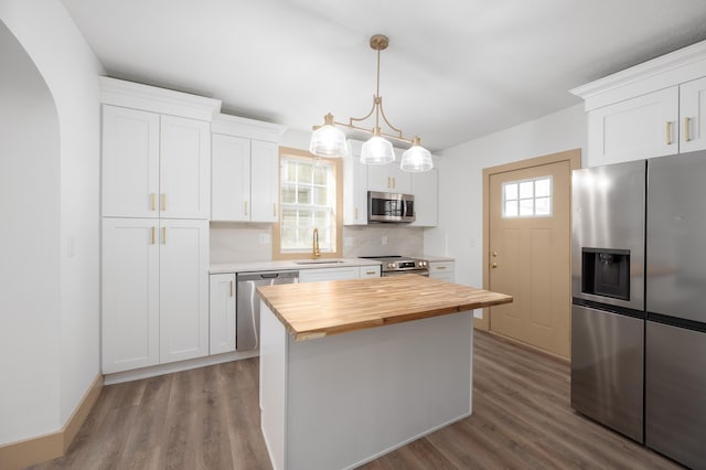 kitchen featuring a sink, appliances with stainless steel finishes, wood counters, and wood finished floors
