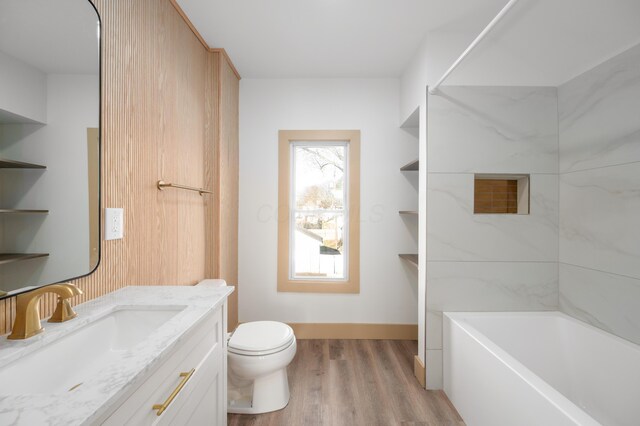 bathroom featuring tub / shower combination, baseboards, toilet, wood finished floors, and vanity