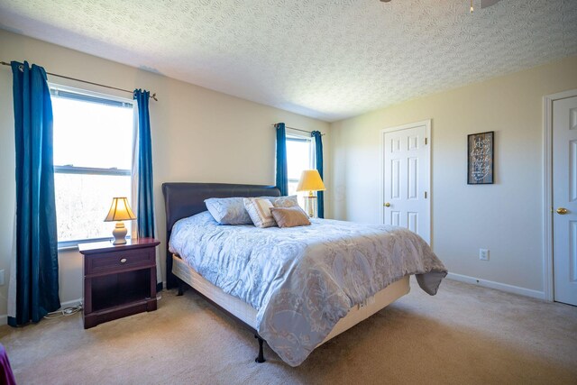 carpeted bedroom featuring a textured ceiling and baseboards