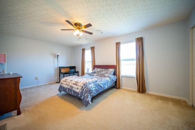 carpeted bedroom featuring visible vents, baseboards, a ceiling fan, and a textured ceiling