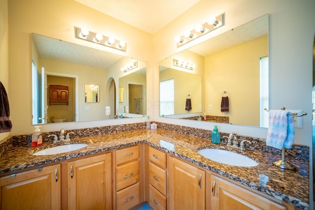 full bathroom featuring a sink, toilet, and double vanity