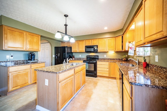 kitchen featuring arched walkways, a sink, black appliances, and dark stone countertops