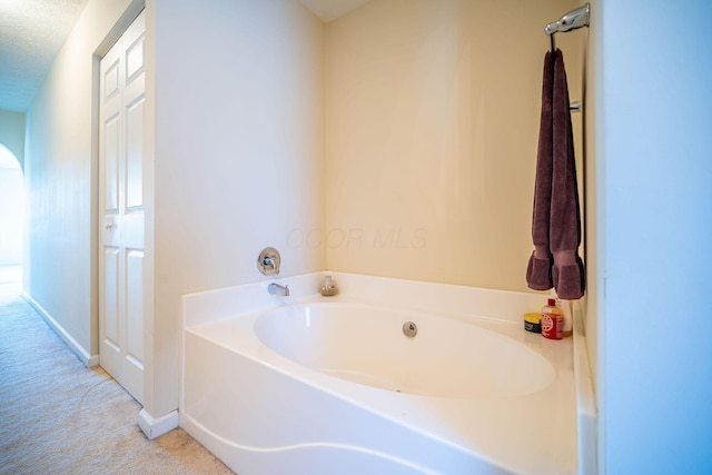full bath with a bath, baseboards, and a textured ceiling
