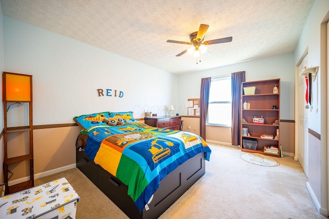 bedroom with ceiling fan, a textured ceiling, carpet flooring, and baseboards