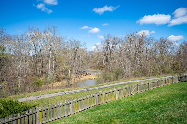 view of yard with a wooded view and fence