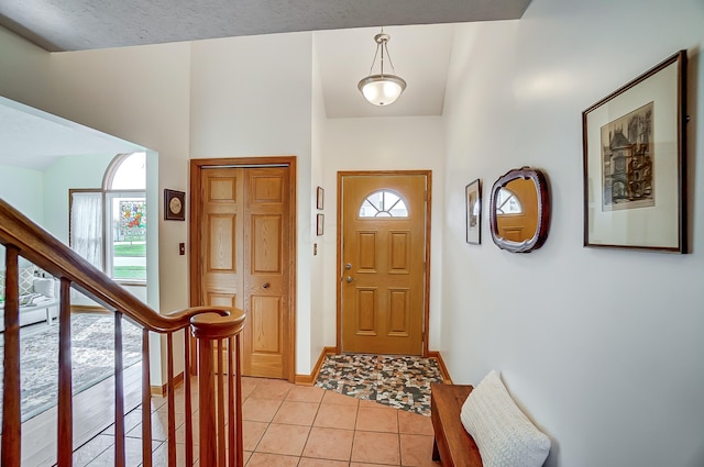 entryway with light tile patterned flooring, stairs, and baseboards
