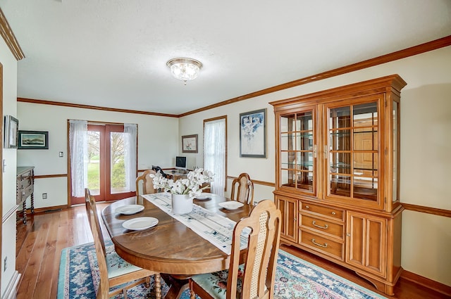 dining room featuring baseboards, light wood-style floors, and ornamental molding