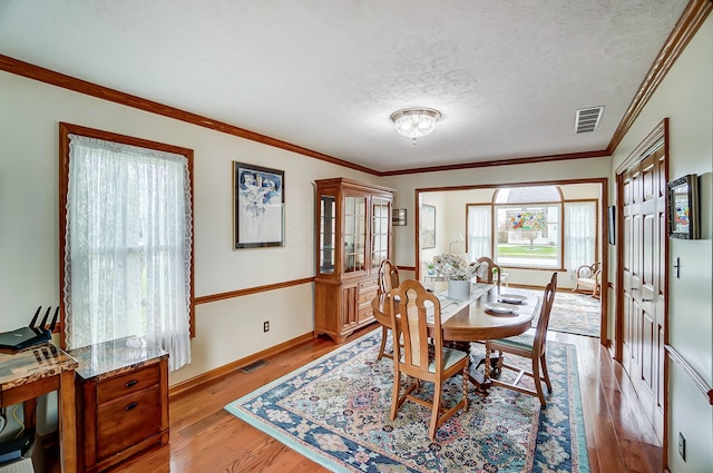 dining area featuring visible vents, light wood-style floors, and ornamental molding