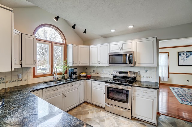 kitchen featuring white cabinetry, a sink, appliances with stainless steel finishes, and lofted ceiling