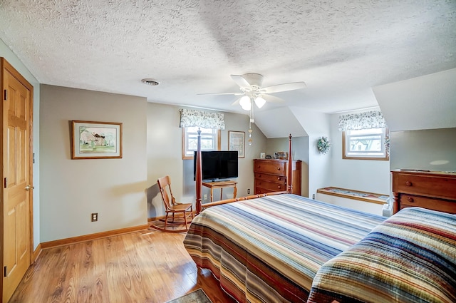 bedroom featuring baseboards, a textured ceiling, visible vents, and wood finished floors