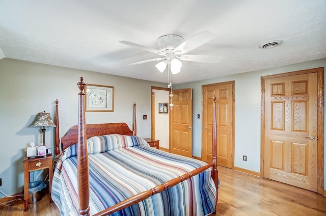 bedroom with baseboards, visible vents, a ceiling fan, and light wood finished floors