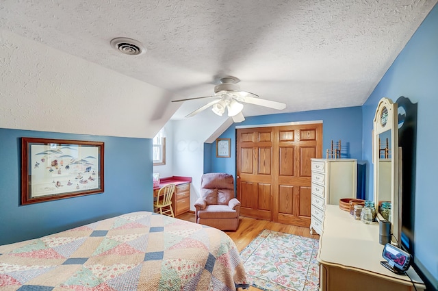 bedroom with lofted ceiling, light wood-style floors, ceiling fan, visible vents, and a closet