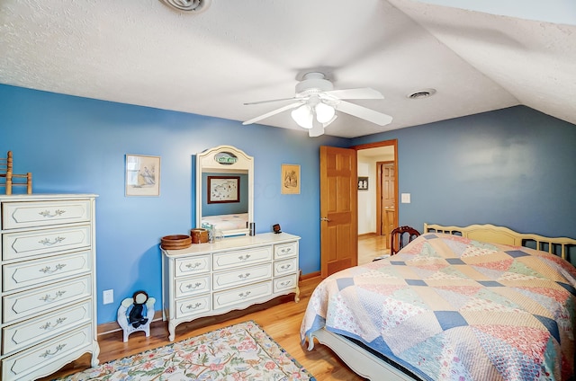 bedroom featuring visible vents, light wood finished floors, baseboards, ceiling fan, and vaulted ceiling