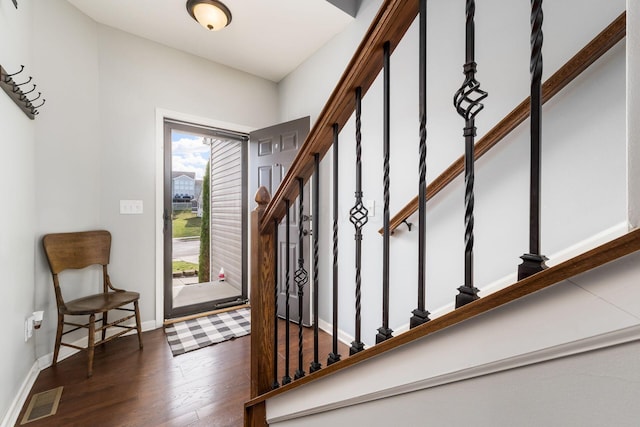 foyer entrance with baseboards, visible vents, stairway, and wood finished floors