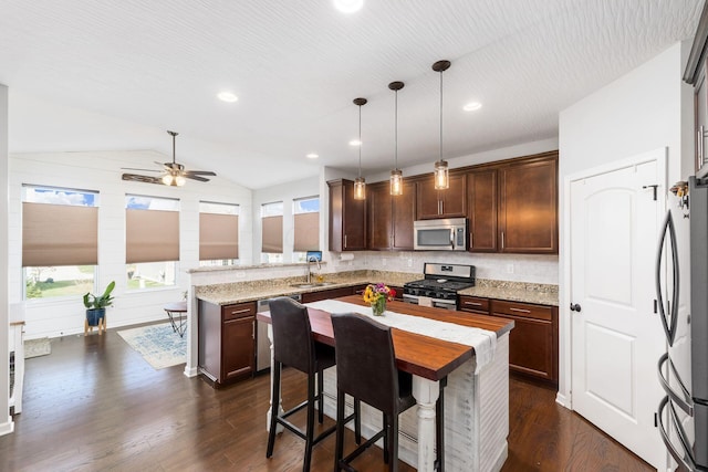 kitchen featuring stainless steel appliances, a sink, a ceiling fan, a peninsula, and dark brown cabinets