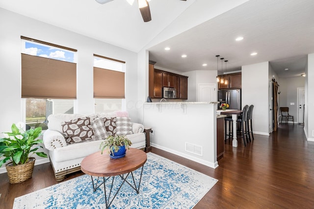 living area featuring dark wood-style flooring, a wealth of natural light, ceiling fan, and visible vents