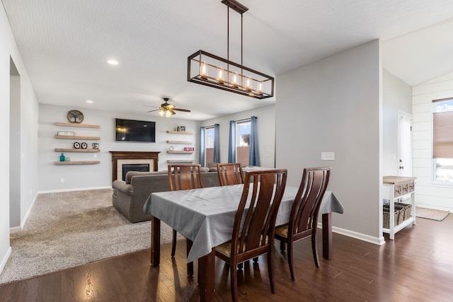 dining area with a fireplace, dark wood finished floors, baseboards, ceiling fan with notable chandelier, and recessed lighting