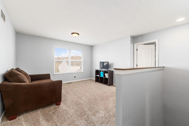 living area with baseboards, carpet, and a textured ceiling