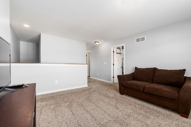 carpeted living room featuring baseboards, visible vents, and a textured ceiling