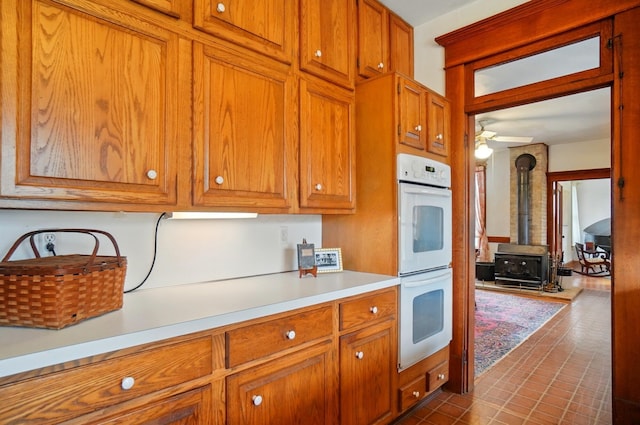 4175 Reynoldsburg Baltimore Rd NW, Baltimore, OH 43105 - kitchen with light countertops, white double oven, a wood stove, and brown cabinets