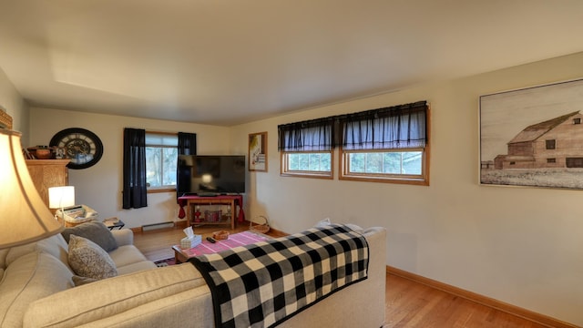 living room with baseboard heating, baseboards, and light wood-style floors