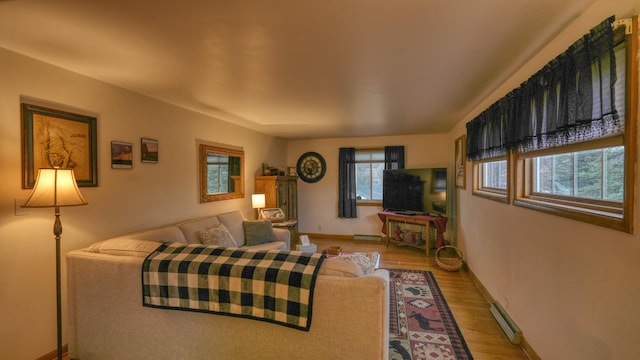 living area with a baseboard heating unit, baseboards, and wood finished floors