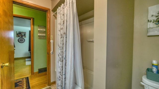 full bath featuring a shower with curtain, toilet, wood finished floors, and baseboards